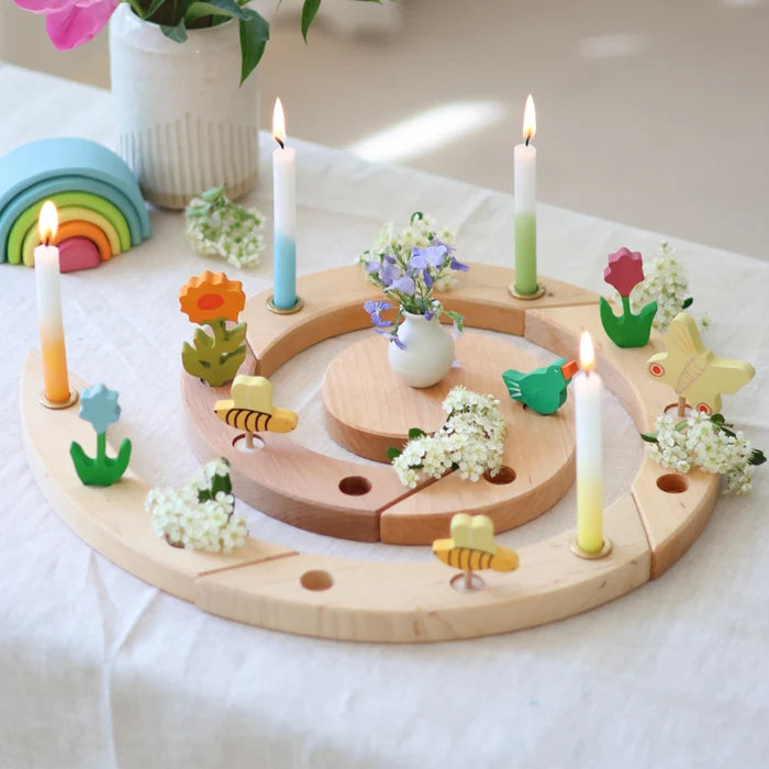Grimm's natural spiral celebration ring with candles and decorative elements on a white surface