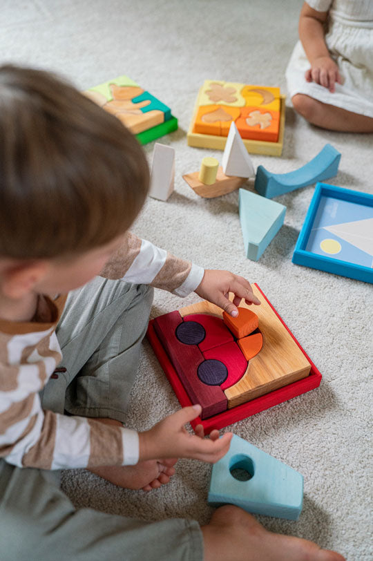 Child playing with a new Grimm's Red Car Stacking Puzzle to represent new Grimm's Wooden Toys for sale at Babipur, official UK stockist.