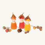 Three Grimm's Rainbow Friends wearing little horse chestnut shell hats with colourful acorns around them