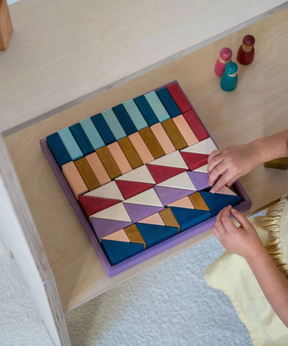 Child arranging different handcrafted wooden Grimms pieces from the rhythm set on a shelf 