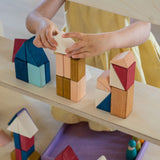 Child stacking different handcrafted wooden Grimms pieces from the rhythm set on a shelf 