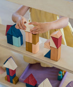 Child stacking different handcrafted wooden Grimms pieces from the rhythm set on a shelf 
