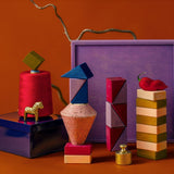 3 simple tower stacks made from handcrafted Grimms wooden pieces from the rhythm set against the purple square 