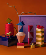 3 simple tower stacks made from handcrafted Grimms wooden pieces from the rhythm set against the purple square 