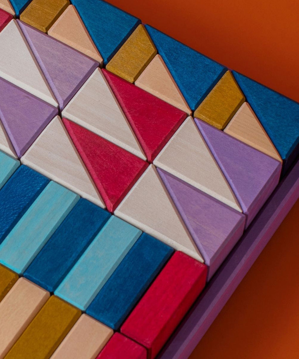 Grimm's wooden rhythm building set, shows handcrafted piece in a purple frame on a brown background.