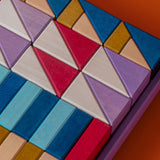 Grimm's wooden rhythm building set, shows handcrafted piece in a purple frame on a brown background.