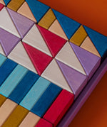 Grimm's wooden rhythm building set, shows handcrafted piece in a purple frame on a brown background.