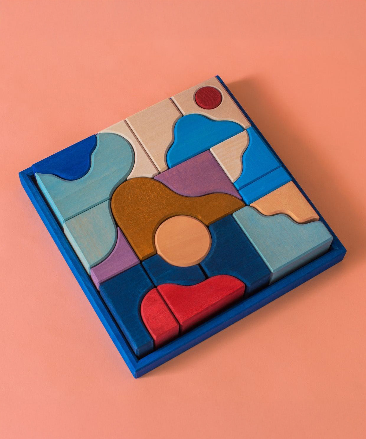 Grimm's wooden wave hand carved pieces in a blue square frame against a light pink background