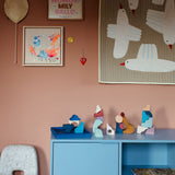 Loose pieces from the Grimms wave hand crafted building set on a blue cupboard in a bedroom setting