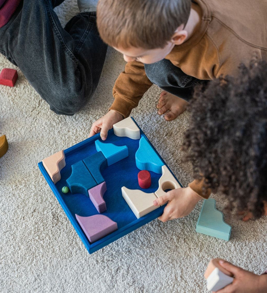 Children playing a game made from the hand crafted Grimm's wooden pieces from the wave set.