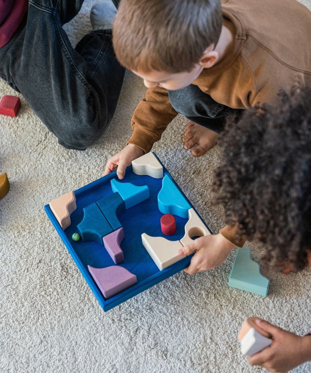Children playing a game made from the hand crafted Grimm's wooden pieces from the wave set.