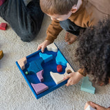 Children playing a game made from the hand crafted Grimm's wooden pieces from the wave set.
