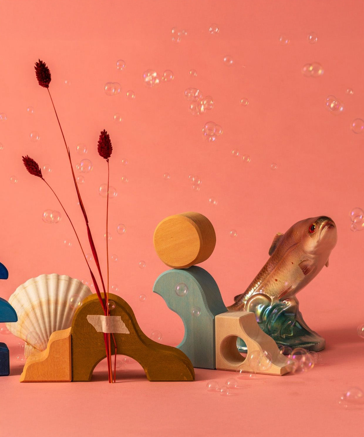 Ocean display using handcrafted Grimms wooden pieces from the wave set against a pink background. 