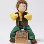 Grimm's Brown Haired Man Doll - Erle is sat down with its legs either side a wooden block of wood, and its arms bent towards its chest. This shows the flexibility of the doll