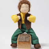 Grimm's Brown Haired Man Doll - Erle is sat down with its legs either side a wooden block of wood, and its arms bent towards its chest. This shows the flexibility of the doll