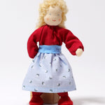 Grimm's Blonde Woman Doll is stood in front of a wooden block of wood, showing how the doll can balance on its feet