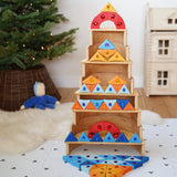 A tower stack made from wooden blocks from the Grimms sparkling mandala set and natural wooden arch pieces