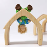 Grimm's Blond Boy Doll - Linde is bent at the waist and is hanging upside down on a Grimm's natural arch to show the flexibility of the doll