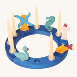 Grimm's 12-Hole Blue Wooden Ring has candles and small Grimm's decorative figures in each hole, and is on a cream background