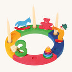 The Grimm's 12-Hole Coloured Wooden Ring with Grimm's decorative figures and candles, celebrating a third birthday