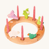 Grimm's 12-Hole Natural Wooden Celebration Ring with pink candles and springtime decorative figures, on a cream background