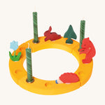 Grimm's Yellow 12-Hole Celebration Ring with decorative figures and green candles on a cream background