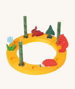 Grimm's Yellow 12-Hole Celebration Ring with decorative figures and green candles on a cream background