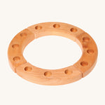 Grimm's 12-Hole Natural Wooden Celebration Ring is made from 4 sections of natural wood with 3 holes in each section, ready for Grimm's decorative figures and candles to be placed inside. The image is on a cream background.