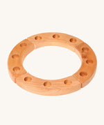 Grimm's 12-Hole Natural Wooden Celebration Ring is made from 4 sections of natural wood with 3 holes in each section, ready for Grimm's decorative figures and candles to be placed inside. The image is on a cream background.