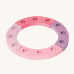 Grimm's 12-Hole Pink-Purple Wooden Celebration Ring on a cream background