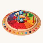 Grimm's Wooden Annual Celebration Ring with Grimm's decorative figures, marbles and a candle ready for a celebration. The image is on a cream background