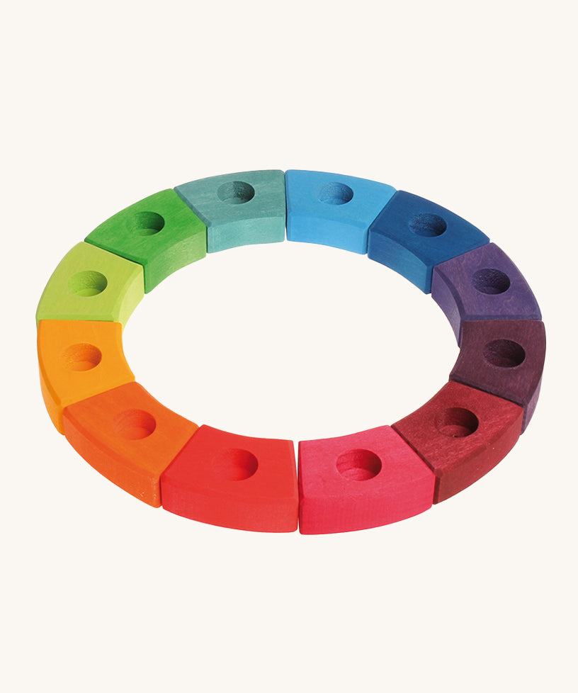 Grimm's 12-Piece Rainbow Birthday Celebration Ring on a cream background. This celebration ring has 12 individual wooden pieces each with a hole in the middle to put Grimm's decorative figures or candles inside