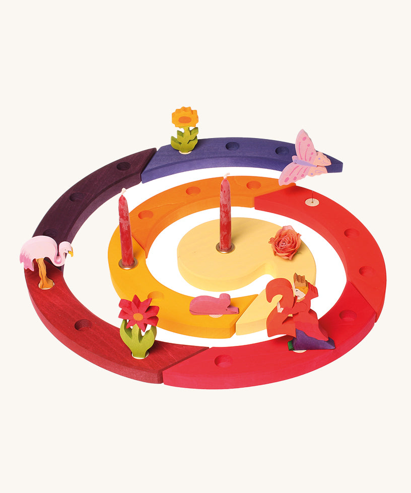 The Grimm's Red Celebration Spiral filled with Grimm's decorative figures and candles, to celebrate a second birthday on a cream background