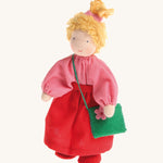 Grimm's Waldorf Blonde Girl Doll wearing a pink top, a red skirt and carrying a green felt bag with a pink flower, on a cream background