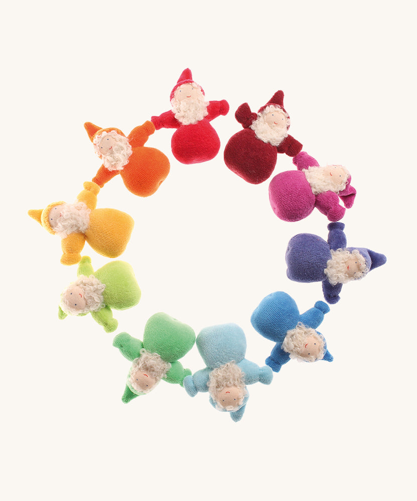 Grimm's Bearded Dwarfs in a circle. These fabric, handmade, waldorf, toy dolls, are one colour of the rainbow in red, orange, yellow, light green, teal, light blue, blue, indigo, pink and magenta. The image is on a cream background
