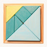 A wooden Tangram puzzle in shades of blue and green sits inside a small light wooden base on a cream background. There are 7 puzzle pieces in different shapes.