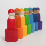 The Grimm's Rainbow Friends with bowls all lined up in a row. The wooden bowls have been turned upside down and the Grimm's Wooden Friend Dolls are stood on top