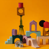 Loose wooden tactile pieces from Grimm's wooden floor set against a orange background.