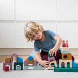 Child building using pieces from the Grimm's wooden floor set on the green frame on a fluffy carpet