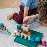Children playing with pieces from the Grimm's wooden floor building set on the green frame on a fluffy carpet