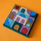 Grimm's wooden floor building set in a green square wooden frame lying flat on a orange surface.