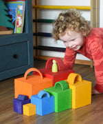 A child playing a sorting game with the Grimm's Large Coloured Boxes Set and mini arch pieces