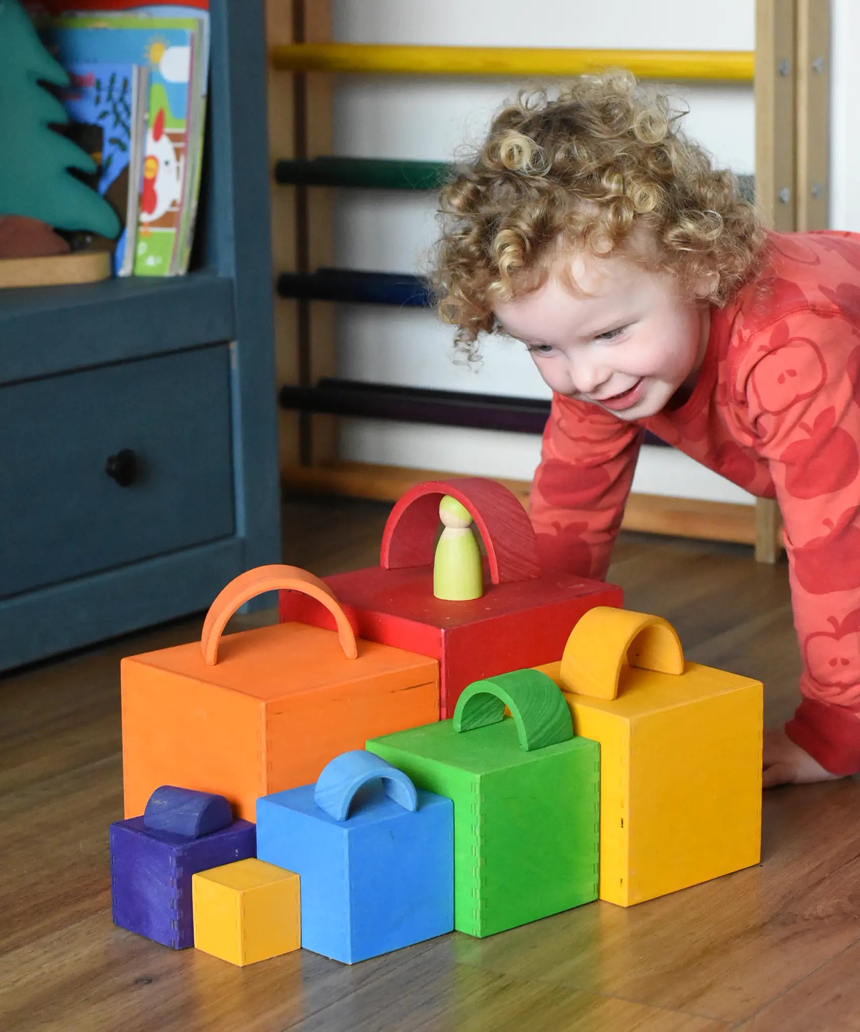 A child playing a sorting game with the Grimm's Large Coloured Boxes Set and mini arch pieces