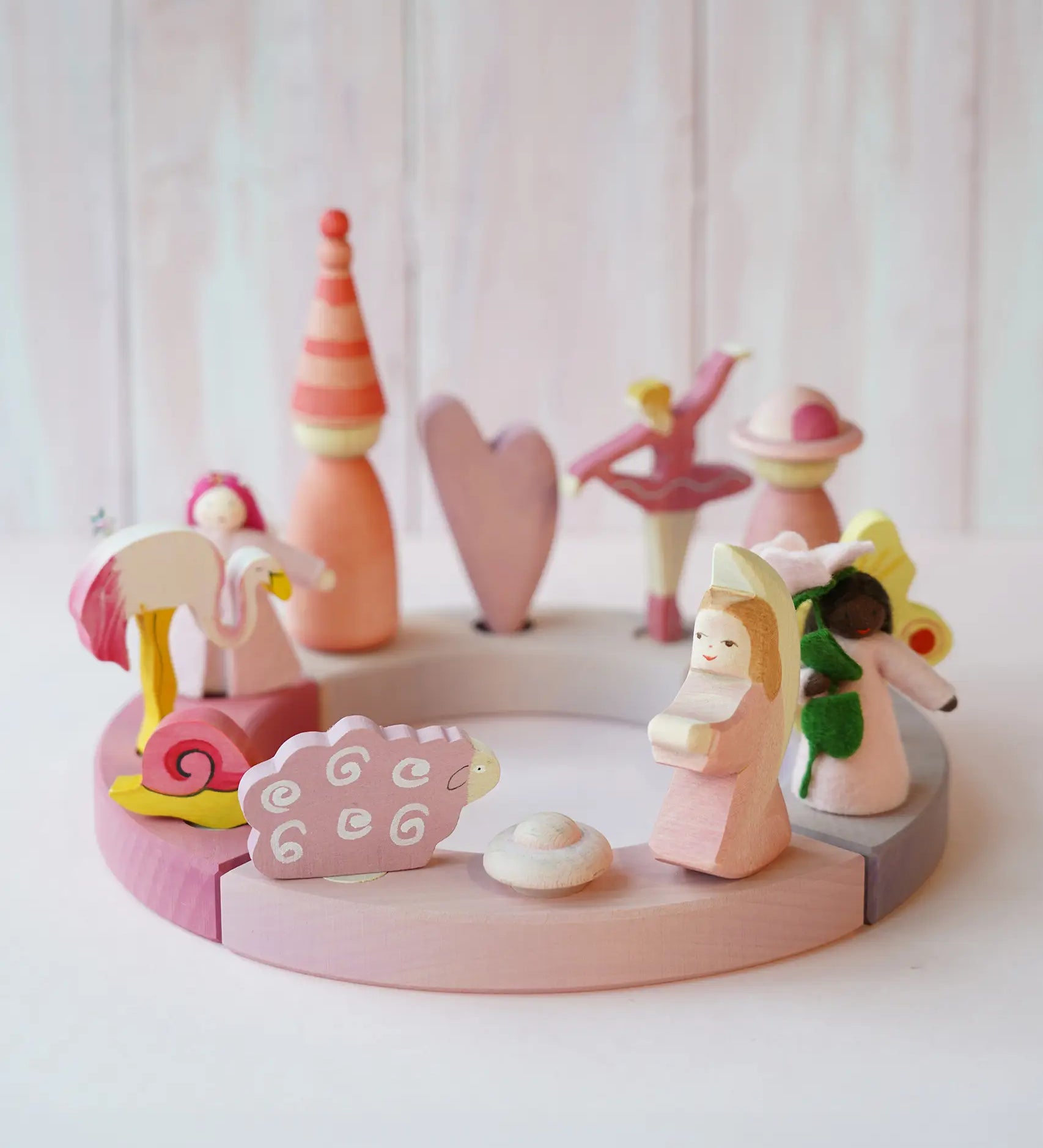 A pink inspired display including Grimms wooden flamingo, snail, ballerina and sheep decorative figure slotted in the celebration ring