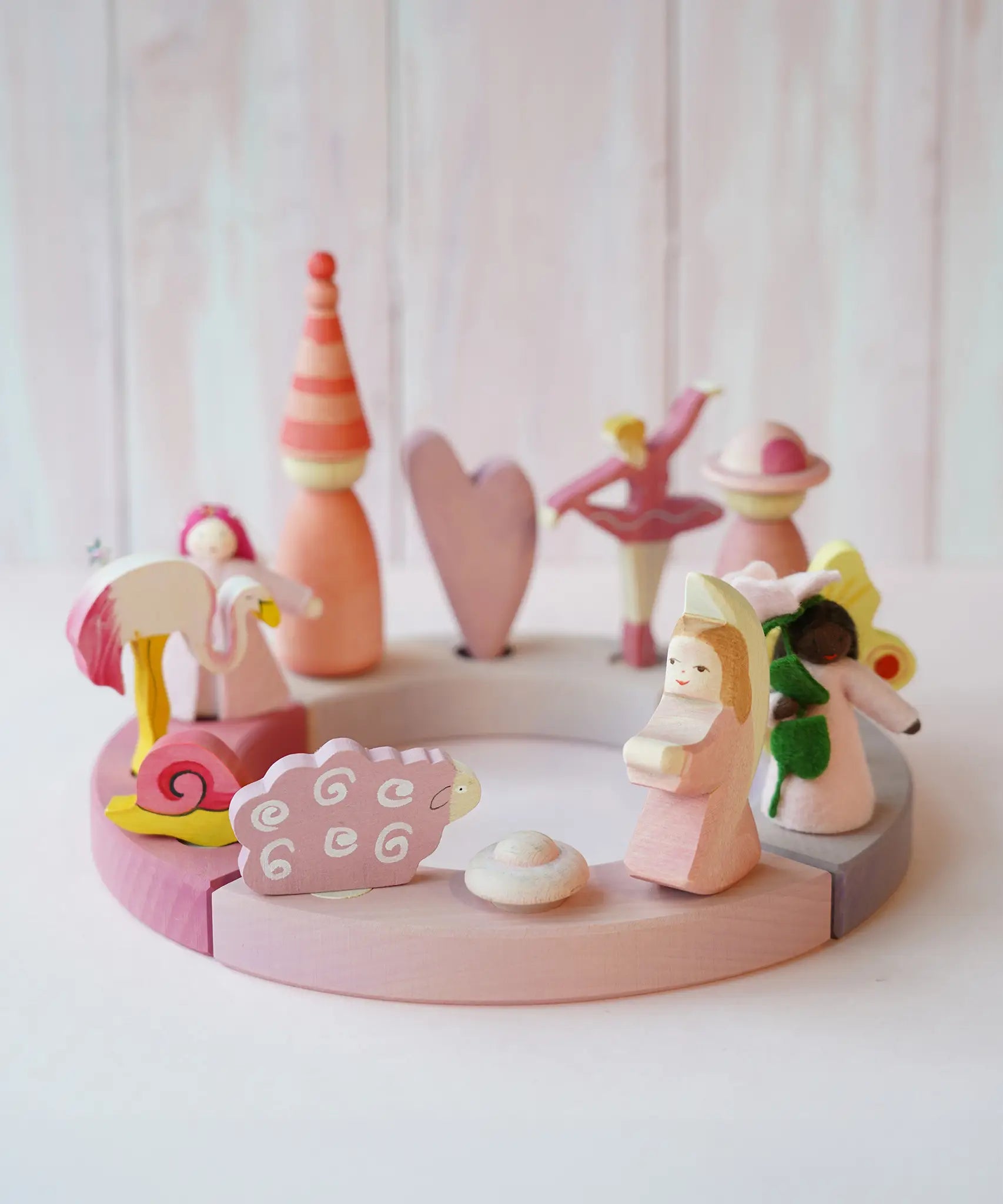 A pink inspired display including Grimms wooden flamingo, snail, ballerina and sheep decorative figure slotted in the celebration ring