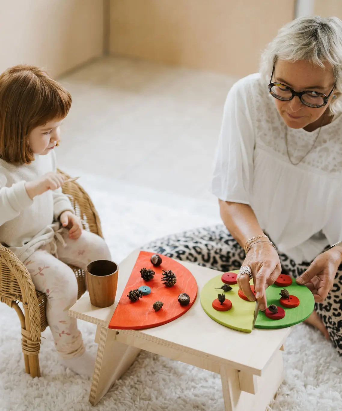 Mother and daughter playing a sorting game using buttons and Grimms bright rainbow semi circle pieces