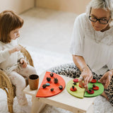 Mother and daughter playing a sorting game using buttons and Grimms bright rainbow semi circle pieces