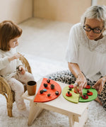 Mother and daughter playing a sorting game using buttons and Grimms bright rainbow semi circle pieces