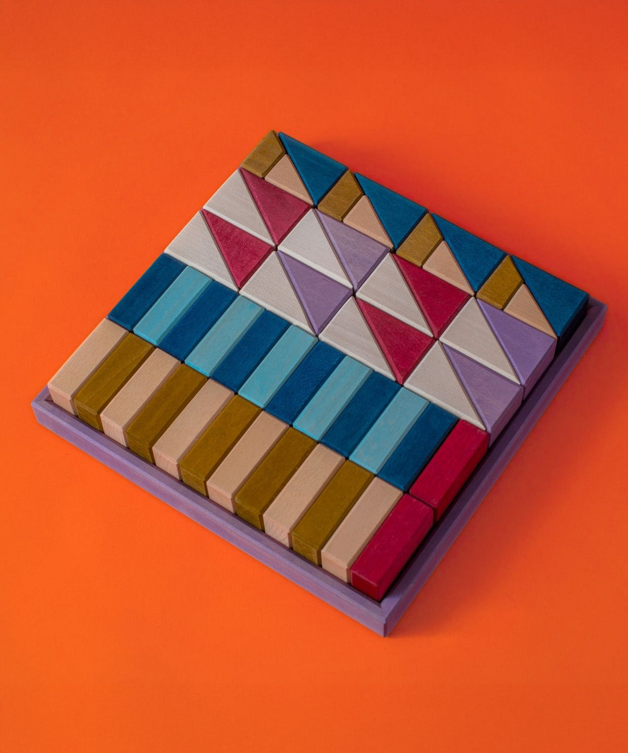 Grimm's wooden rhythm hand crafted pieces in a purple square frame against a orange background
