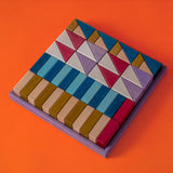 Grimm's wooden rhythm hand crafted pieces in a purple square frame against a orange background